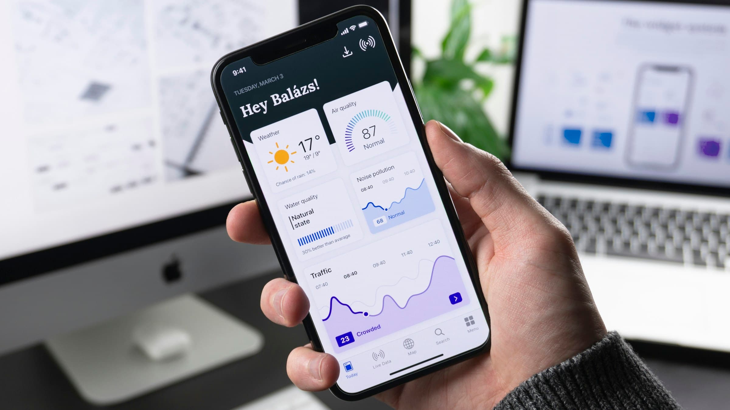 A hand holding a smartphone running a polished mobile app.